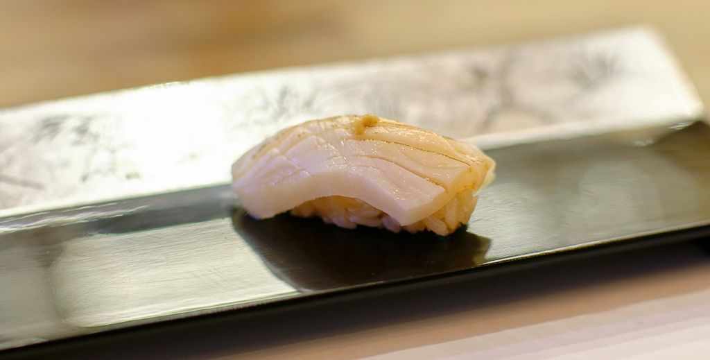 Ein Nigiri Sushi, das mit der Zutat Escolar zubereitet wurde, liegt auf einer kleinen Platte in einem Sushi-Restaurant.