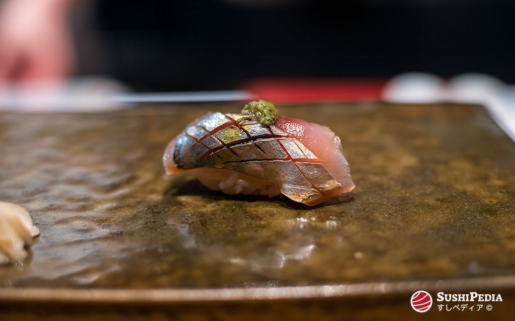 Aji Sushi Nigiri serviert auf einer traditionellen Steinplatte.