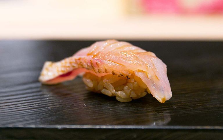 Sorgfältig zubereitetes Akamutsu Nigiri Sushi auf einem glänzenden schwarzen Teller, mit einem Hauch von Sojasauce für den perfekten Geschmack.