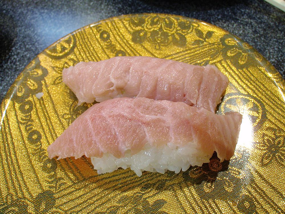 Two pieces of Bincho Toro nigiri sushi, served on a gold-patterned plate, highlighting the elegant simplicity of Japanese sushi artistry.