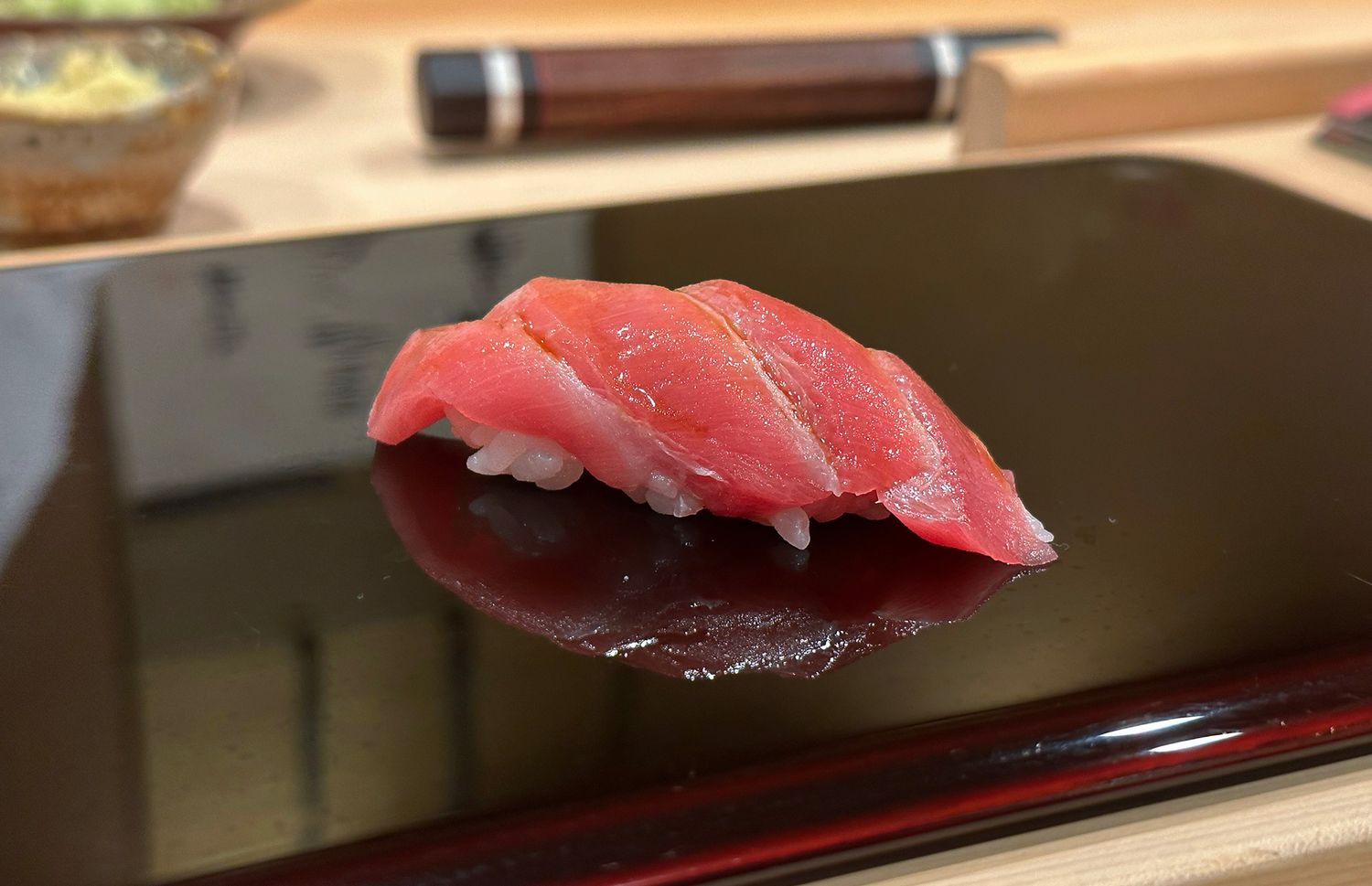 An der Bar eines Sushi-Restaurants liegt ein frisch zubereitetes Stück Nigiri-Sushi mit fettem Thunfisch (japanisch Otoro) auf einem Serviertablett.