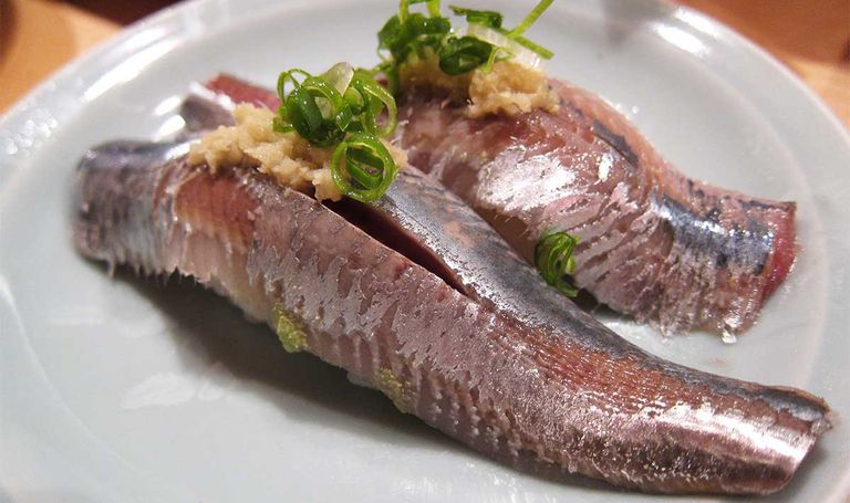 Zwei Stücke Iwashi Sardine Sushi mit Ingwer und gehacktem Lauch auf weißem Teller