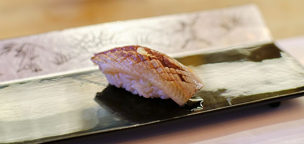 Nahaufnahme von Iwashi-Sushi Nigiri auf einer rechteckigen Platte mit japanischem Dekor