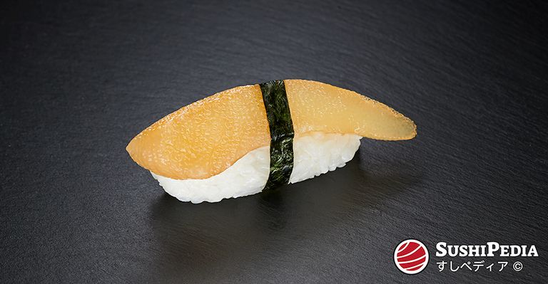 Ein frisch zubereitetes Stück Nigiri-Sushi mit Heringsrogen (japanisch Kazunoko) liegt auf einer Steinplatte.