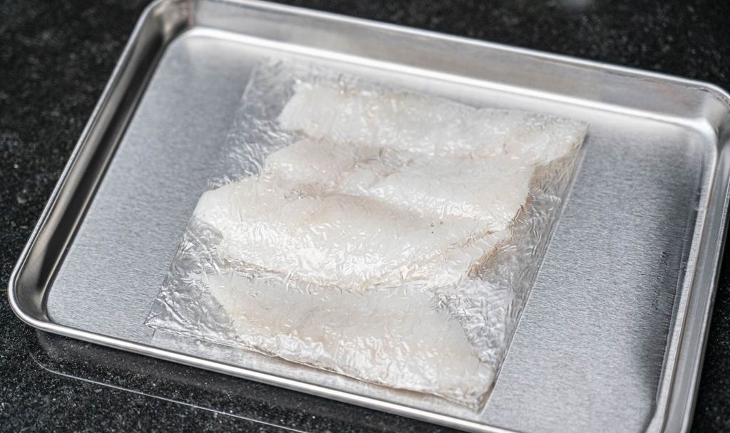 Sashimi-Stücke auf einem Tablett, eingewickelt in Pichitto-Folie zur Dehydration. Die Folie hilft, überschüssige Feuchtigkeit zu entfernen und die Frische des Fisches zu bewahren.