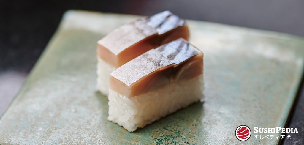 A close-up image of two pieces of Saba Battera sushi, perfectly pressed and topped with silver shimmering skin, presented on a traditional Japanese ceramic plate.