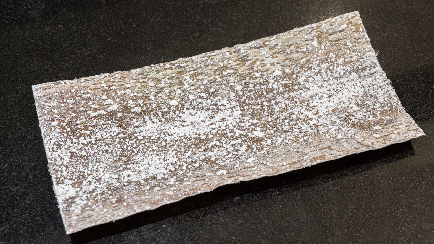 A rectangular sheet of shiroita kombu (white sheet kombu) with a fine white surface, lying flat on a dark background.