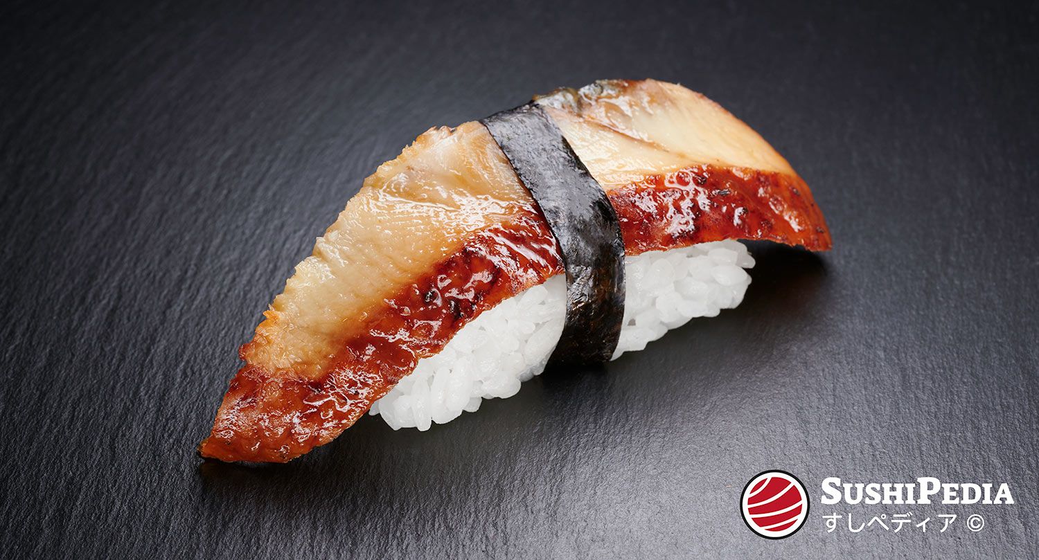 Ein Stück Unagi Nigiri Sushi, bei dem eine glänzende, gegrillte Aal-Scheibe auf einem Bett aus lockerem, weißem Sushi-Reis liegt, umwickelt mit einem schmalen Streifen Nori. Das Sushi präsentiert sich auf einer dunklen, schieferfarbenen Oberfläche. Im rechten unteren Eck befindet sich das Logo von SushiPedia.