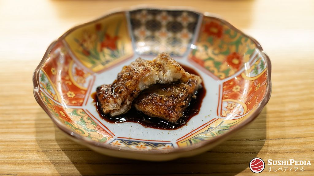Gegrillter Unagi in einer kunstvollen Schale, glasiert mit einer dunklen, glänzenden Sauce (unagi-no-tare).