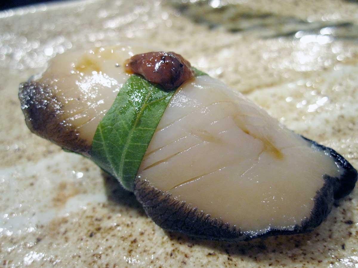 Abalone with Shiso and Pum Sauce as Nigiri Sushi on a plate. 
				TheDeliciousLife. 
				Live Abalone with Shiso and Pum Sauce. 
				flickr.com. 
				Attribution 2.0 Generic (CC BY 2.0). 
				