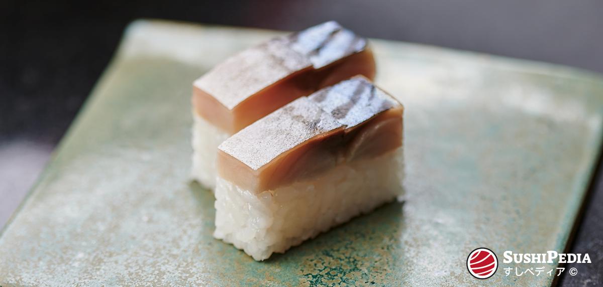 Gepresstes Makrelen (saba) Sushi, das auf einer glasierten Tonplatte liegt.