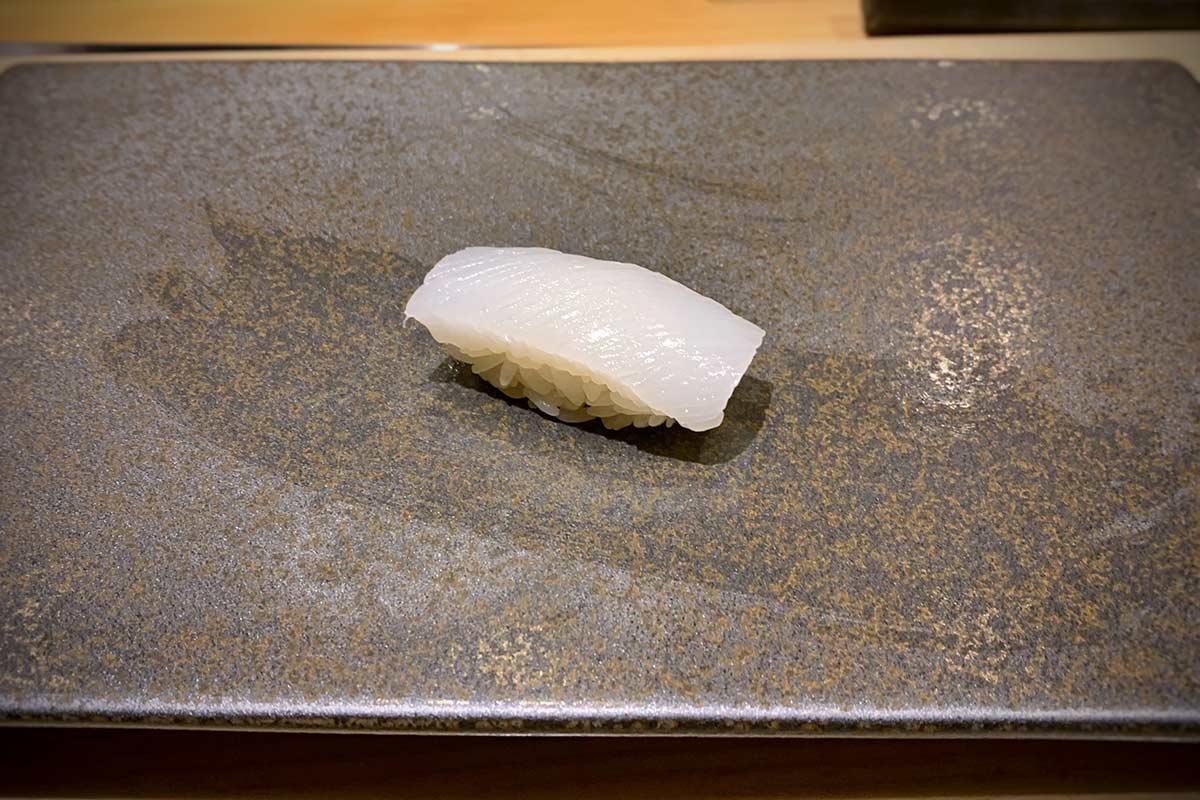 Squid (ika) sushi nigiri on a plate. 
				T.Tseng. 
				Aori ika, Sushi Amane, New York NY. 
				flickr.com. 
				Attribution 2.0 Generic (CC BY 2.0). 
				